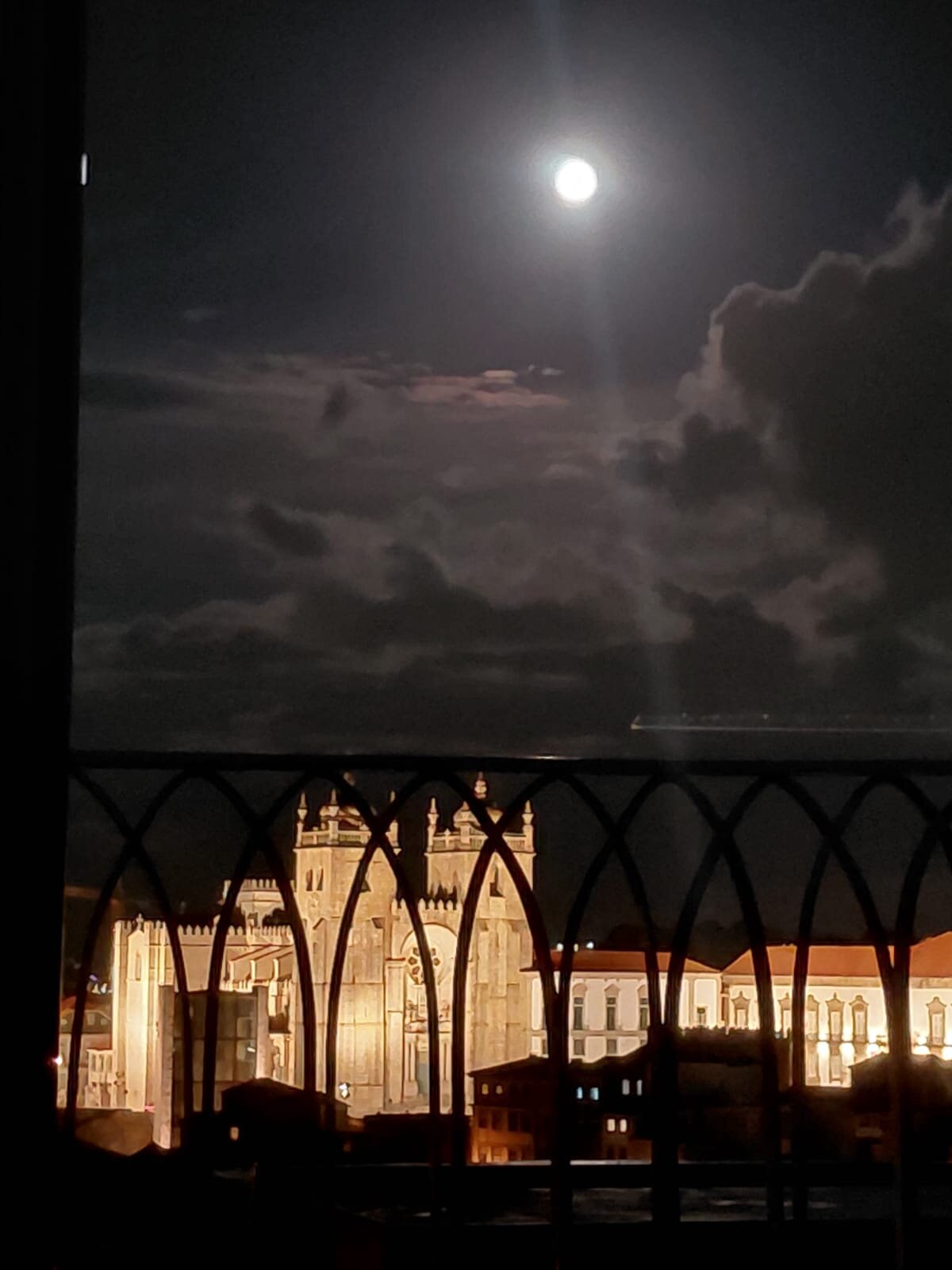 Detail of the balcony's iron railing with the illuminated Sé Cathedral in the background at night